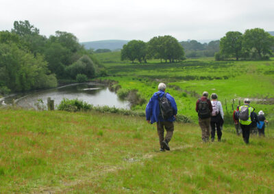 Photo of walkers approaching a fishing lake on the way to Sharford Bridge – May 8, 2024