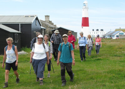 Photo of walkers with Portland Bill Lighthouse in the background – June 22, 2024