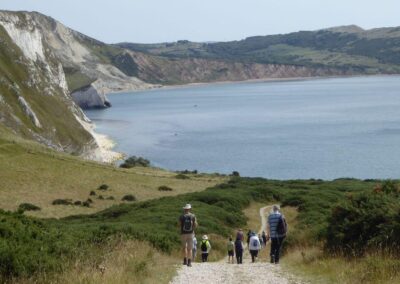 Photo of walkers descending hill towards Mupe Bay – August 17, 2024