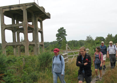 Photo of walkers passing Holton Heath's derelict WWII anti-aircraft gun towers – August 31, 2024