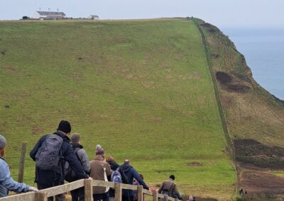 Photo of walkers heading down the long fight of steps from Emmetts Hill with cottages at St Aldelm's Head in the distance – January 18, 2025